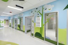 an empty hospital hallway with painted trees on the walls and doors to other rooms in it