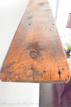 a piece of wood hanging from the side of a wall next to a light fixture