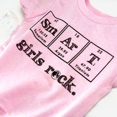 a pink shirt with the names and symbols of some type on it, sitting on a white surface