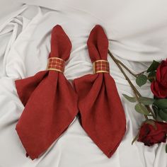 two red ties laying on top of a white sheet next to flowers and a rose