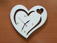 a heart shaped clock with two hearts cut out of it's sides on a wooden surface