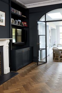 a living room with black walls and wooden floors, a tv on the wall and a fireplace