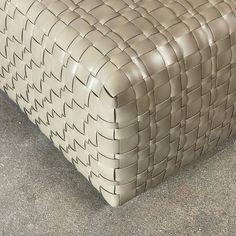 a beige leather bench sitting on top of a cement floor