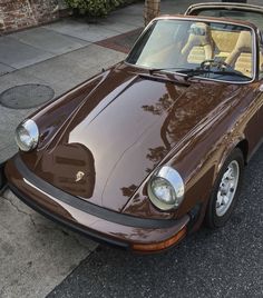 a brown sports car is parked on the street