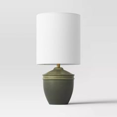 a table lamp with a white shade on it's base and a green vase underneath