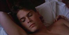 a shirtless man laying in bed with his eyes closed