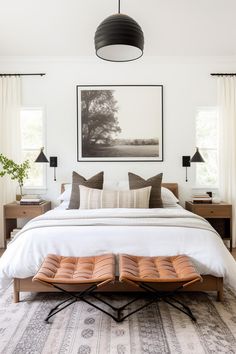 a bedroom with a bed, two lamps and pictures on the wall