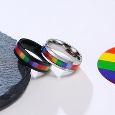 two rings that are sitting next to each other on a white surface with a rainbow ring in the middle