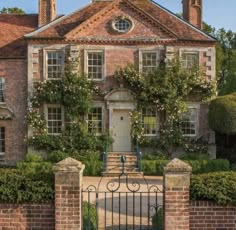 an old brick house with ivy growing on it's walls and gated entrance