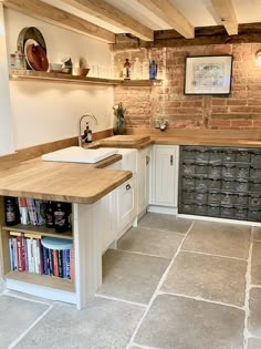 a kitchen with white cabinets and wooden shelves filled with books on top of each shelf