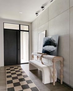 a white bench sitting in the middle of a room next to a black and white checkered floor