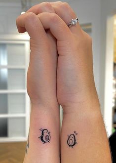 two people with matching tattoos on their arms, one holding the other's hand