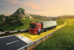 a man standing next to a semi truck on a highway with mountains in the background