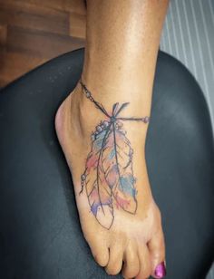 a woman's foot with a tattoo on it and a feather attached to the ankle