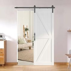 an open barn door in a living room with white walls and wood flooring on the side