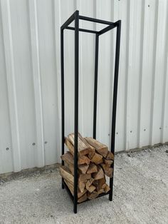 a stack of firewood sitting in front of a white building with a metal frame