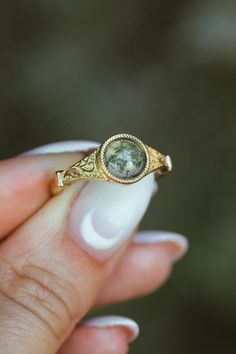 Product Details Ring Style: The "Selene" is an accented-style moss agate women's engagement ring. Many other center stone options are available upon request. Center Stone: 7mm Round Cut Moss Agate Materials: 14K gold engagement ring featuring a moss agate center stone Customizable: Because each ring is handcrafted to order, we can customize yours using unique materials, gemstones, or design features, often without any added cost! We can even use personal materials that you send! Basic ... Untraditional Unique Engagement Rings, Creative Engagement Rings Vintage, Bohemian Wedding Rings Melanie Casey Fine Jewelry, Affordable Classic Crystal Engagement Ring, Affordable Classic Wedding Crystal Ring, Affordable Classic Crystal Wedding Ring, Cheap Classic Crystal Engagement Ring, Earthy Wedding Rings Set, Boho Stone Wedding Ring