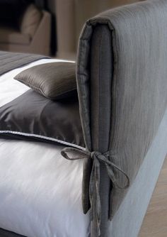 a close up of a bed with two pillows on it and a pillow tied to the headboard