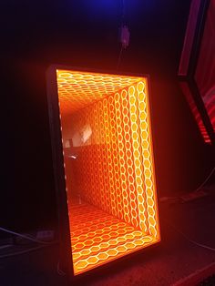 an orange and yellow lit up cube in the middle of a dark room with lights on it