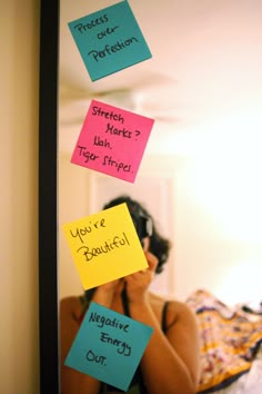 a woman looking at herself in the mirror with sticky notes attached to her face and head