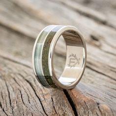 a wedding ring that is sitting on top of a piece of wood