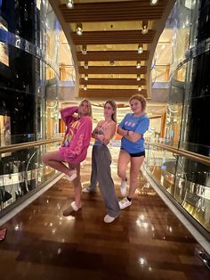 three girls are standing on the escalator in a mall