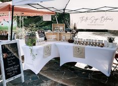 an outdoor market with tables covered in white linens and bottles on display under umbrellas