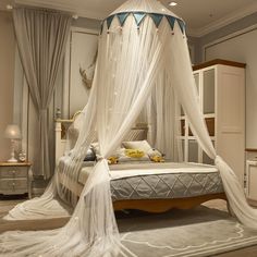 a white canopy bed in a bedroom next to a night stand and dresser with drawers