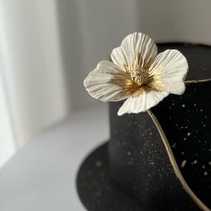 a white flower on top of a black hat