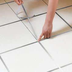 a person is using a pair of scissors to cut the tile on the kitchen floor