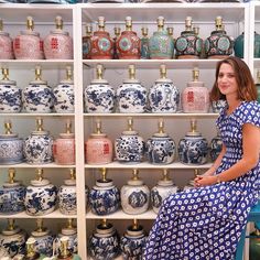 a woman is sitting on a chair in front of shelves with vases and jars