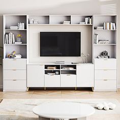 a living room with white furniture and a flat screen tv mounted on a wall unit