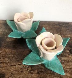 two ceramic flowers sitting on top of a wooden table