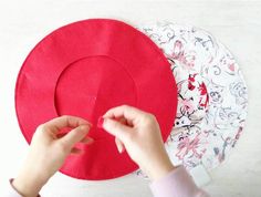 someone is making a paper hat out of red material on the table with other plates