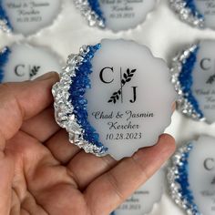 a hand holding a small white and blue wedding ornament