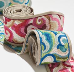 two rolls of multicolored fabric on white surface with one rolled up and the other rolled down