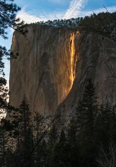 the sun is shining down on a tall waterfall