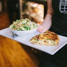 a person is holding a plate with food on it and a bowl of salad in the other hand