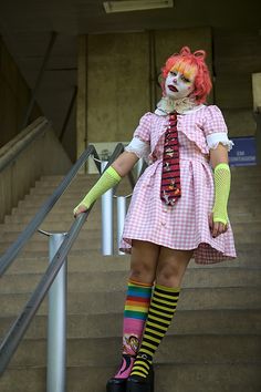 a woman dressed as a clown is standing on the stairs with her hands in her pockets