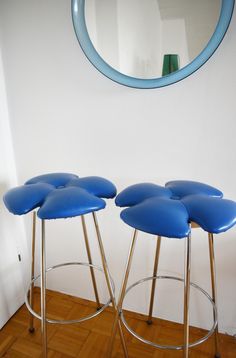 two blue stools sitting next to each other in front of a mirror on the wall