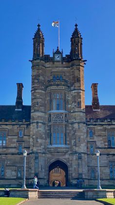 an old building with a clock on the front and two flags flying in the air