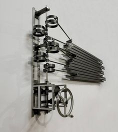 a clock mounted to the side of a wall with multiple pieces of art hanging on it