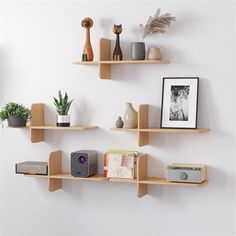 three wooden shelves on the wall with pictures and other items in them, one is empty