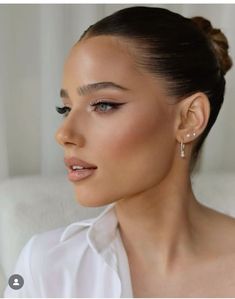 a woman in white shirt and earrings looking off to the side