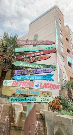 many signs are posted on the side of a building in front of a palm tree