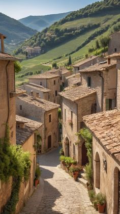 an alley way with stone buildings and green hills in the background