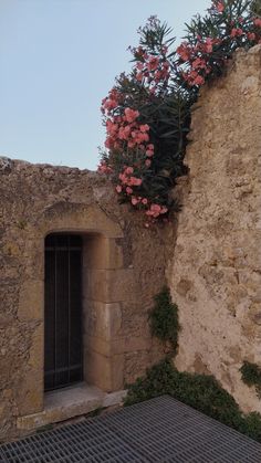 an old stone building with flowers growing out of it