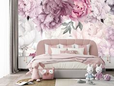 a bedroom with pink flowers on the wall and stuffed animals sitting in front of it