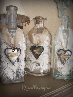 three glass bottles with hearts in them sitting on a table next to lace doily