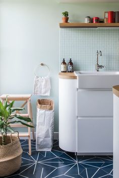 a white sink sitting under a window next to a wooden shelf filled with pots and plants